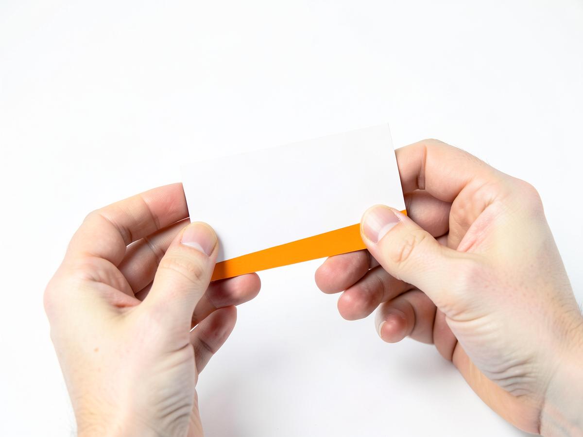 Hands holding a white business card with an orange band